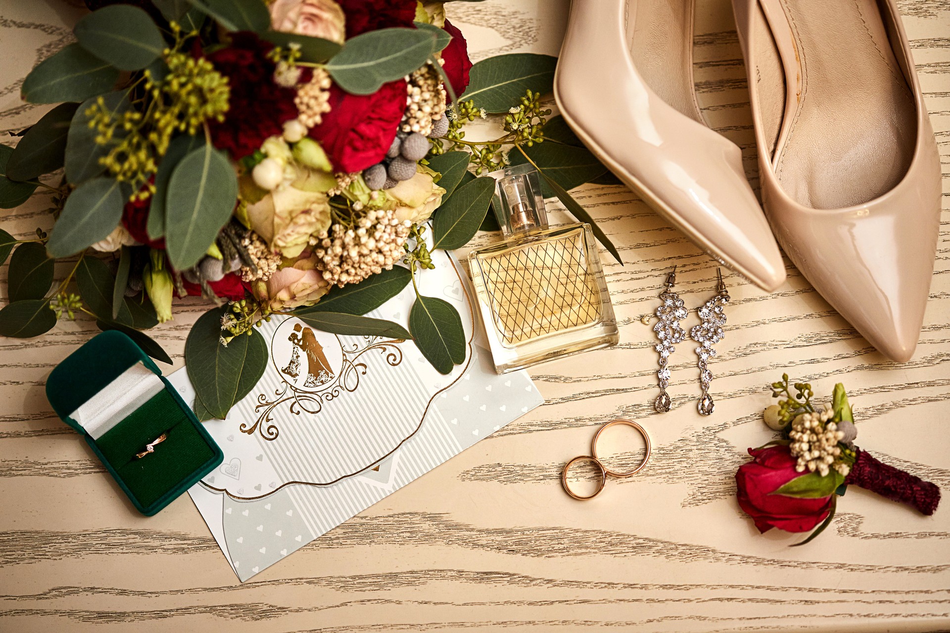 accesorios nupciales como zapatos, ramo, anillo y perfume yacen en una mesa